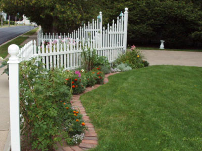 A dream garden welcome - the entrance to the driveway is surrounded with flowers along the white picket fence.