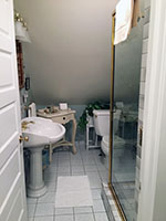 The Heritage Suite private bath features a large glass and brass walk-in shower.