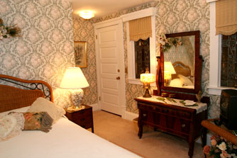 An antique dresser nestles between two antique leaded glass windows.