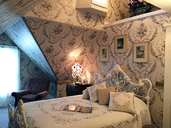 A chandalier shines down from the cathedral ceiling as dolls peek down from the loft above the queen-sized angel bed.