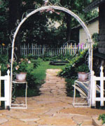 A stone path leads through an arch  to the "secret garden" behind the carriage house
