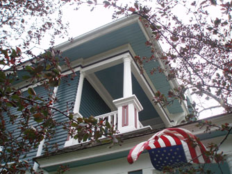 The balcony soars above the front porch, where a flag waves in a strong breeze.
