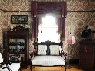 The windows peek from behind the curtains to reveal their leaded glass.